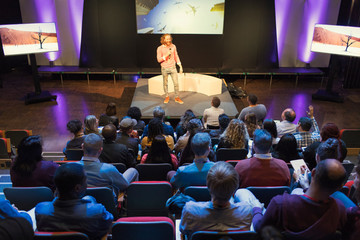 Audience listening to male speaker on stage