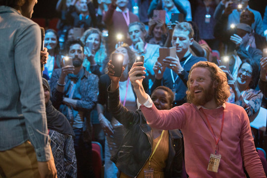 Smiling audience using smart phone flashlights for speaker