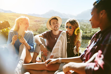 Smiling young friends enjoying picnic in sunny summer park