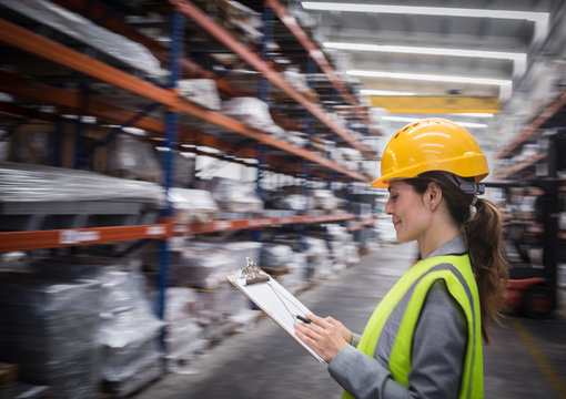 Female supervisor with clipboard checking inventory in steel warehouse