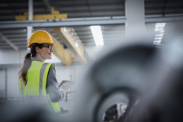 Confident female worker using digital tablet in steel factory