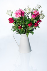 Dewy white, red and pink roses in vintage beige watering can