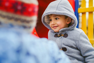 Two boys small friends or brothers having fun at park in winter or autumn day on the slide wearing...
