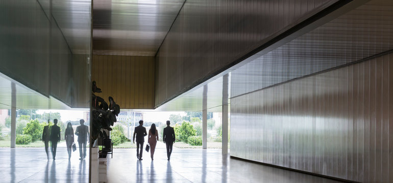 Silhouette business people walking in modern corridor