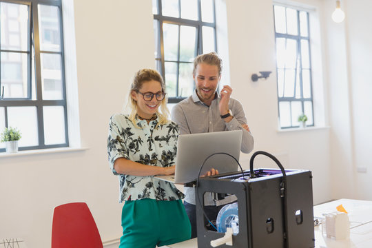 Designers using laptop at 3D printer in office