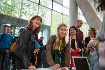 Smiling businesswomen arriving, checking in at conference registration table