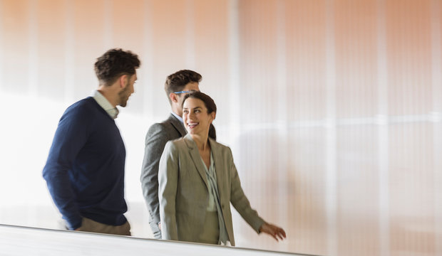 Smiling business people talking and walking in corridor