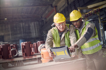 Steelworkers using laptop in steel mill