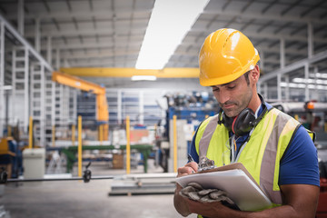 Male worker writing on clipboard in factory