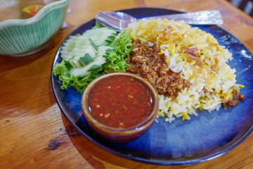 Beef Biryani, Stew Beef with yellow rice serve with spicy sauce on side on blue plate in restaurant. 