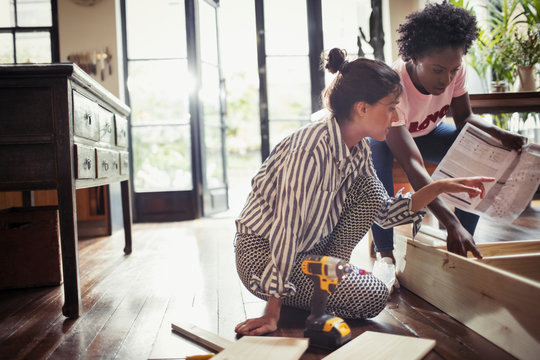 Women with instructions assembling furniture