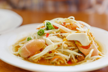 Close up view of Thai spicy green papaya salad, Som Tum, with salted duck egg.