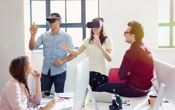 Computer programmers testing virtual reality simulator glasses in office