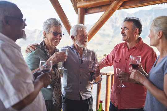 Happy active senior friends drinking wine on balcony