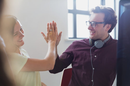 Enthusiastic creative business people high-fiving in office