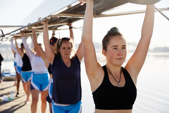 Confident, determined female rowing team lifting scull overhead