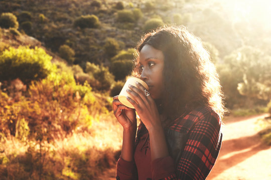 Young woman drinking coffee in sunny woods