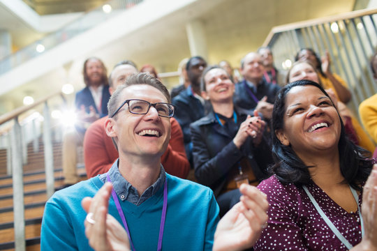 Laughing, happy conference audience clapping