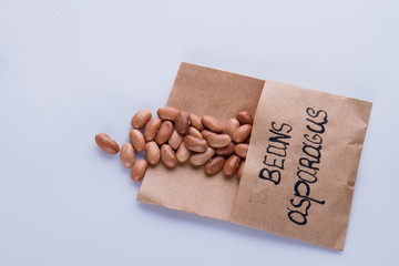 Asparagus bean concept. Brown beans in a paper package isolated on white background.
