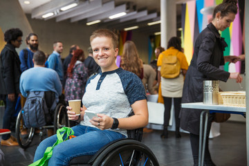 Portrait smiling, confident woman in wheelchair using smart phone at conference