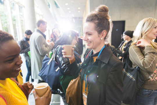 Smiling businesswomen talking and drinking coffee at conference