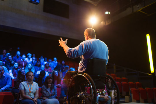 Audience watching male speaker in wheelchair talking on stage