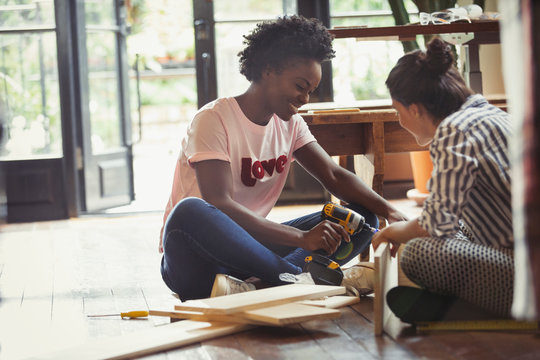 Women assembling furniture with power drill