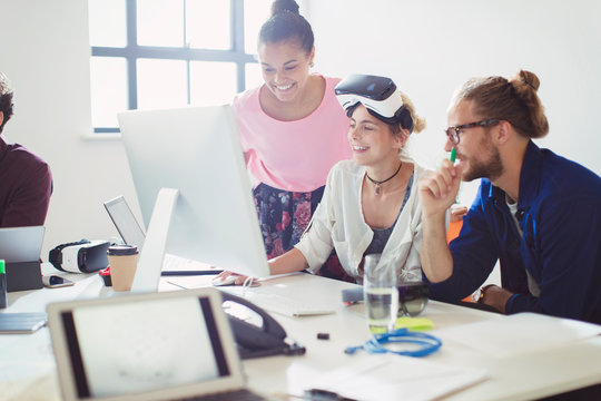Computer programmers programming virtual reality simulator glasses at computer in office