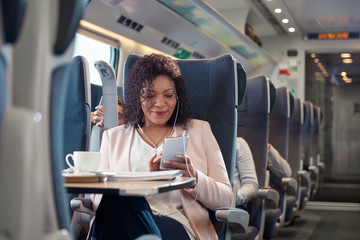 Businesswoman working listening to music headphones smart phone on passenger train
