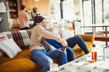 Playful woman playing video game on living room sofa