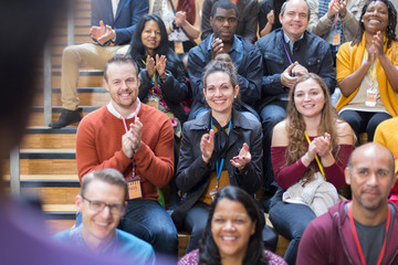 Smiling audience clapping for speaker at conference