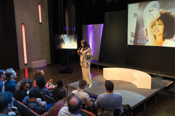 Female speaker in hijab on stage talking to audience