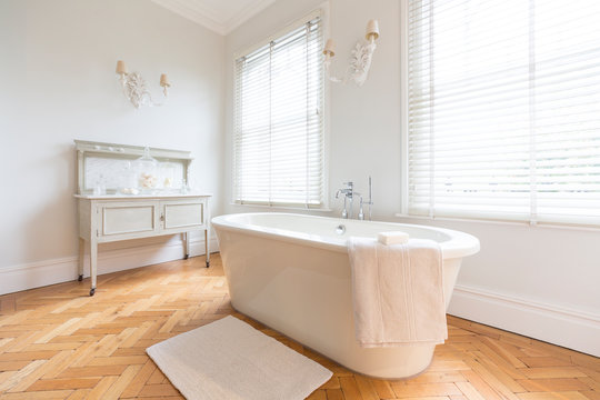 White, luxury home showcase interior bathroom soaking tub parquet hardwood floor
