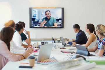 Designers video conferencing with colleague in conference room meeting