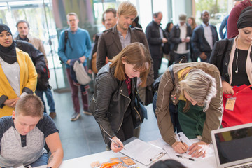 Business people arriving, checking in at conference registration table