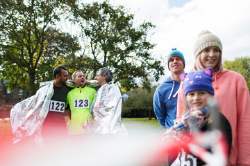 Male marathon runners wrapped in thermal blanket in park