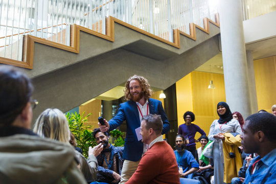 Smiling male speaker giving microphone to woman in audience