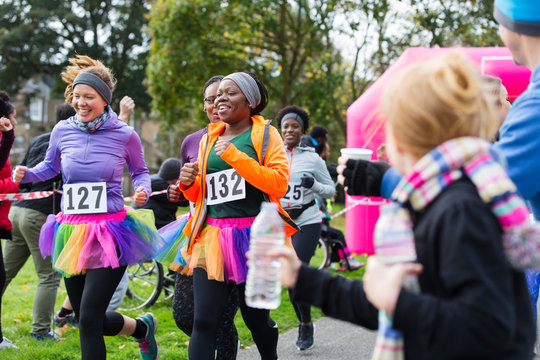 Female runners in tutus running at charity race in park