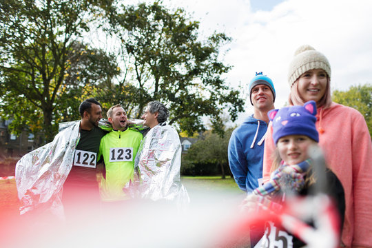 Male marathon runners wrapped in thermal blanket in park