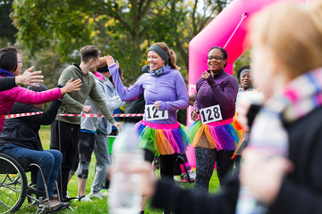 Female runners high-fiving spectators at charity run finish line