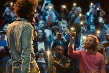 Audience using smart phone flashlights, watching speaker