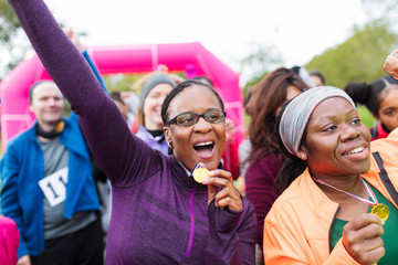 Enthusiastic female runners medals cheering, celebrating at charity run