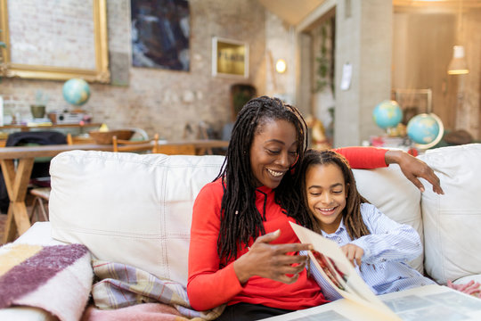 Mother and daughter looking at photo album on sofa