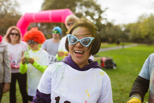 Portrait playful female runner in silly sunglasses at charity run in park