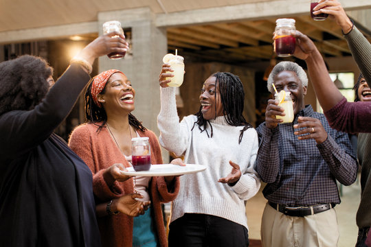 Enthusiastic multi-generation family toasting lemonade sangria on patio
