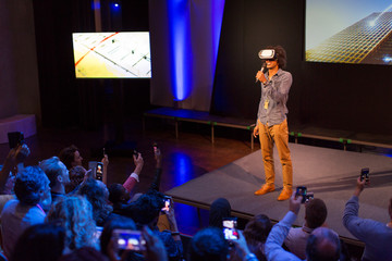 Audience watching male speaker with virtual reality simulator glasses on stage