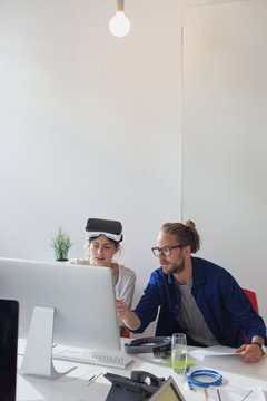 Computer programmers programming virtual reality simulator glasses at computer in office