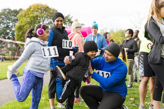 Family runners preparing, stretching at charity run in park