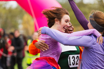 Enthusiastic female runners finishing charity run, celebrating