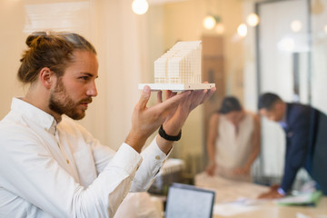 Focused, curious male architect examining model